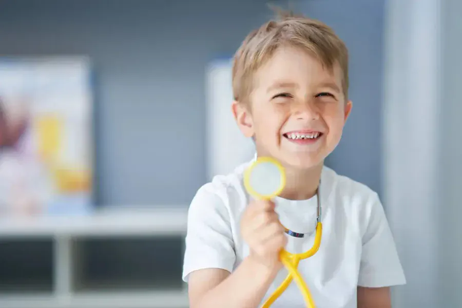 Niño sonriendo con un estetoscopio después de su consulta con la neumóloga pediatra