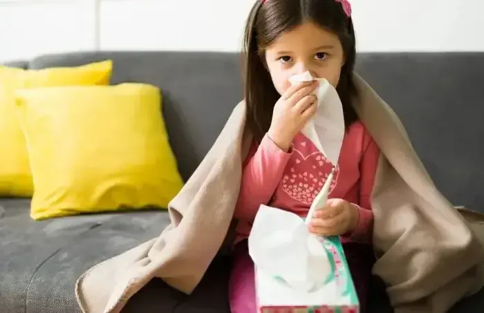 Niña con gripe envuelta en una cobija, infección respiratoria aguda