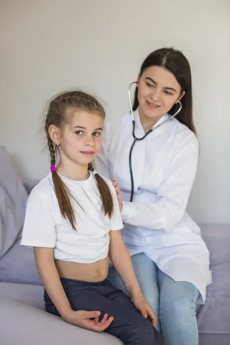 Doctora auscultando con estetoscopio a una niña por bronquitis