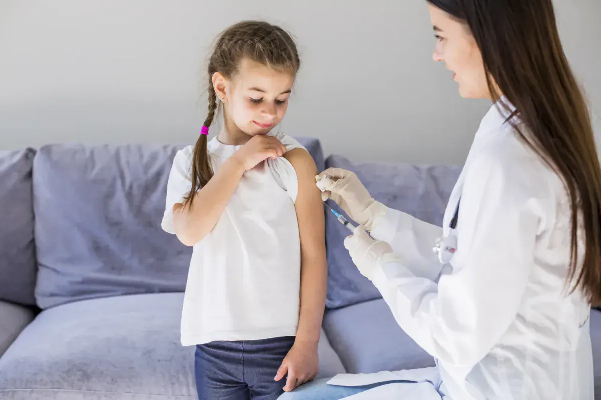Doctora aplicando una vacuna contra enfermedades respiratorias en el brazo de una niña